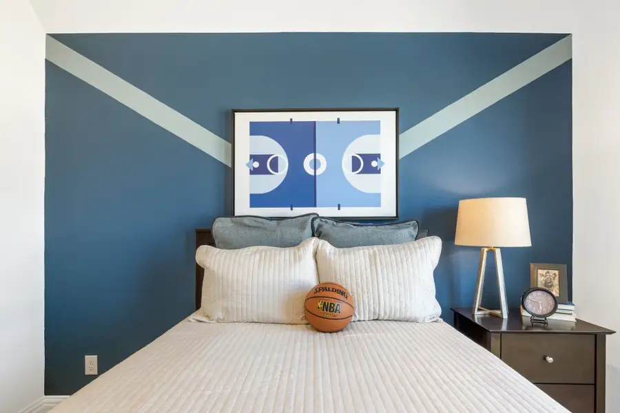 Kids bedroom with blue accent wall, basketball court artwork, and basketball on the bed