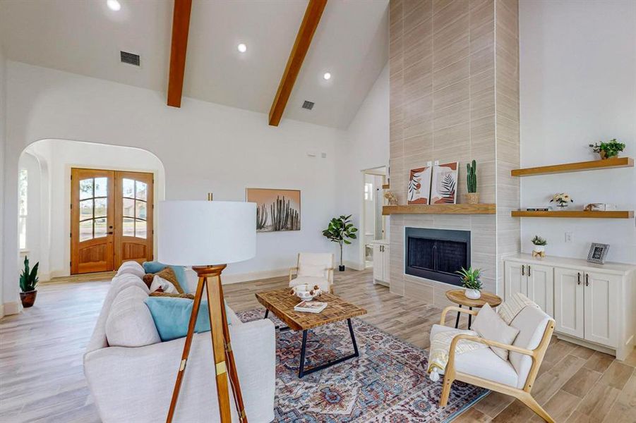 Living room featuring high vaulted ceiling, a fireplace, light hardwood / wood-style floors, and beam ceiling