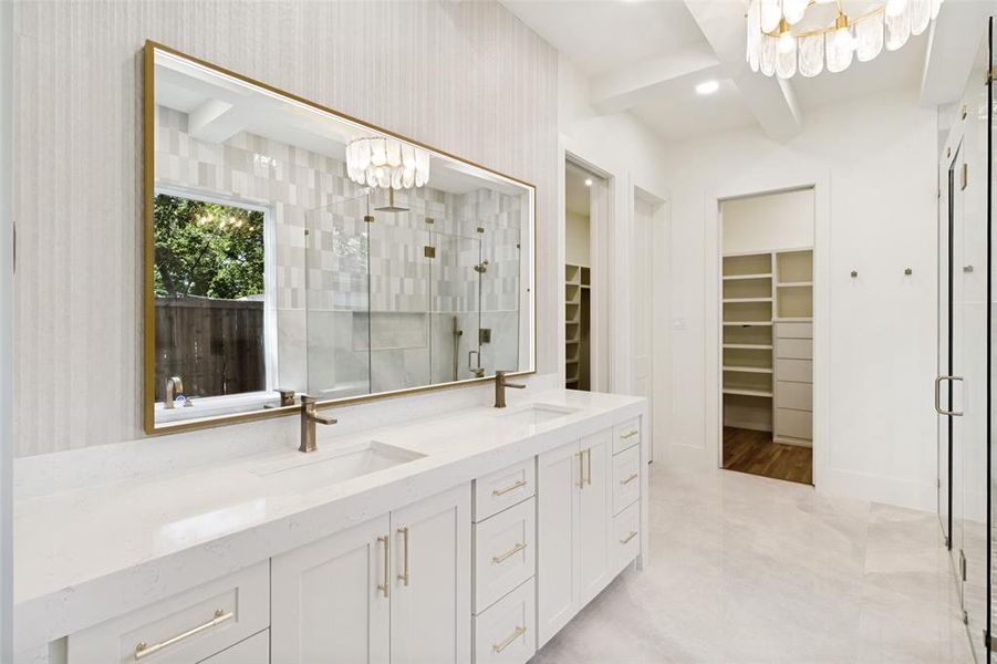 Dual vanity with white cabinetry, gold-toned hardware, and integrated sinks Dual vanity with white cabinetry, gold-toned hardware, and integrated sinks