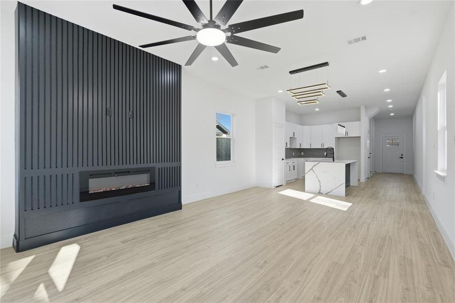 Unfurnished living room featuring a glass covered fireplace, light wood-type flooring, recessed lighting, and a ceiling fan Unfurnished living room featuring a glass covered fireplace, light wood-type flooring, recessed lighting, and a ceiling fan