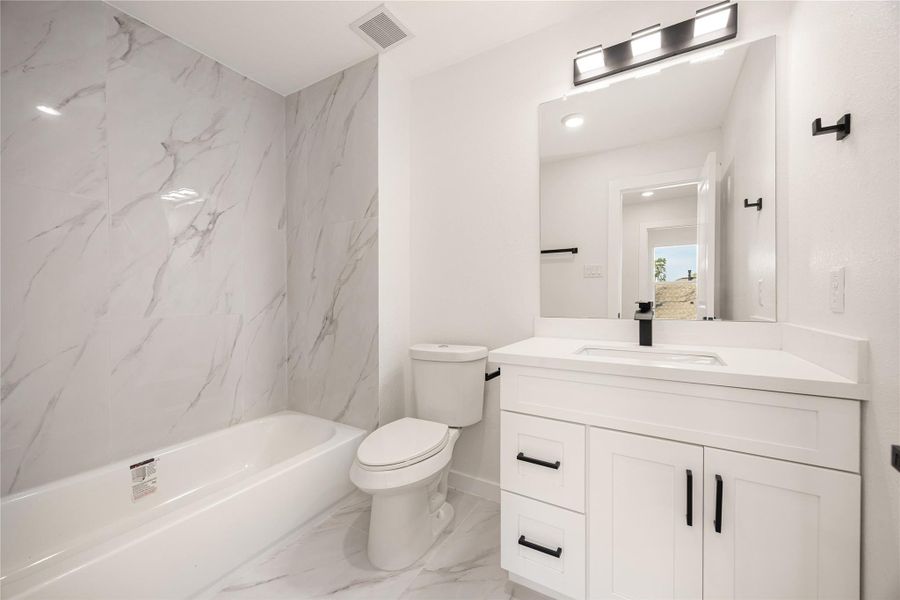 Secondary bathroom featuring a modern vanity with quartz countertop, sleek black fixtures, and a tub/shower combo with contemporary tile surround, offering a bright and functional design. Secondary bathroom featuring a modern vanity with quartz countertop, sleek black fixtures, and a tub/shower combo with contemporary tile surround, offering a bright and functional design.