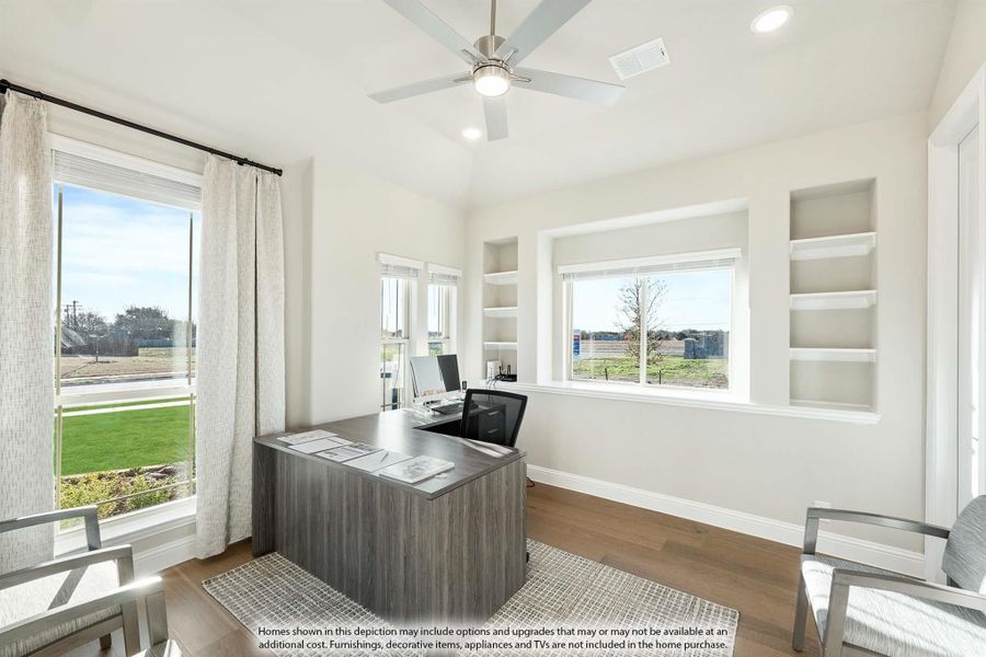 Home office with wood desk, built-in shelves, ceiling fan, and large windows with natural light