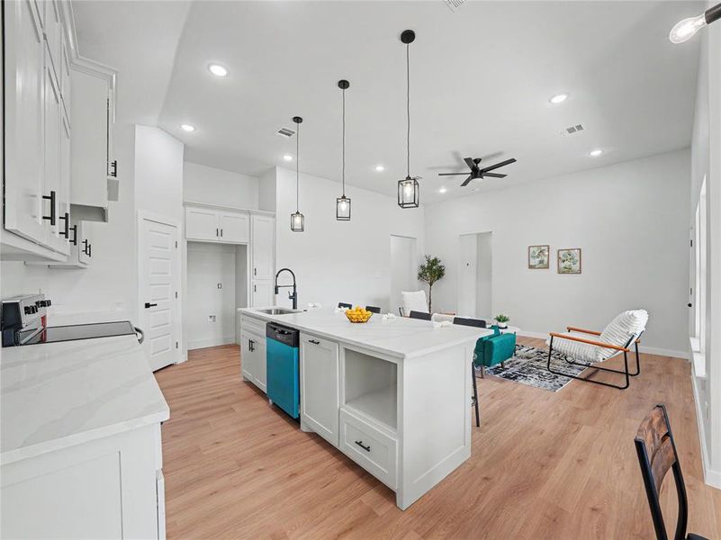 Kitchen with white cabinets, a center island with sink, electric range, and light wood-style flooring