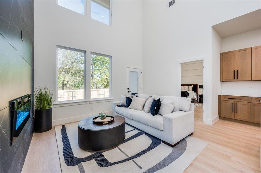 Living room with light hardwood / wood-style floors and a high ceiling