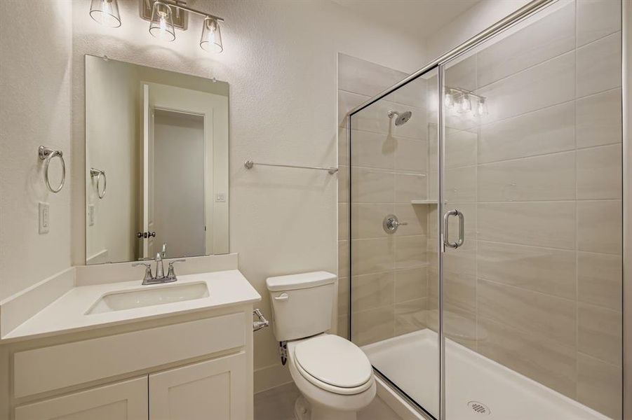 Bathroom with a shower stall, vanity, and a textured wall Bathroom with a shower stall, vanity, and a textured wall