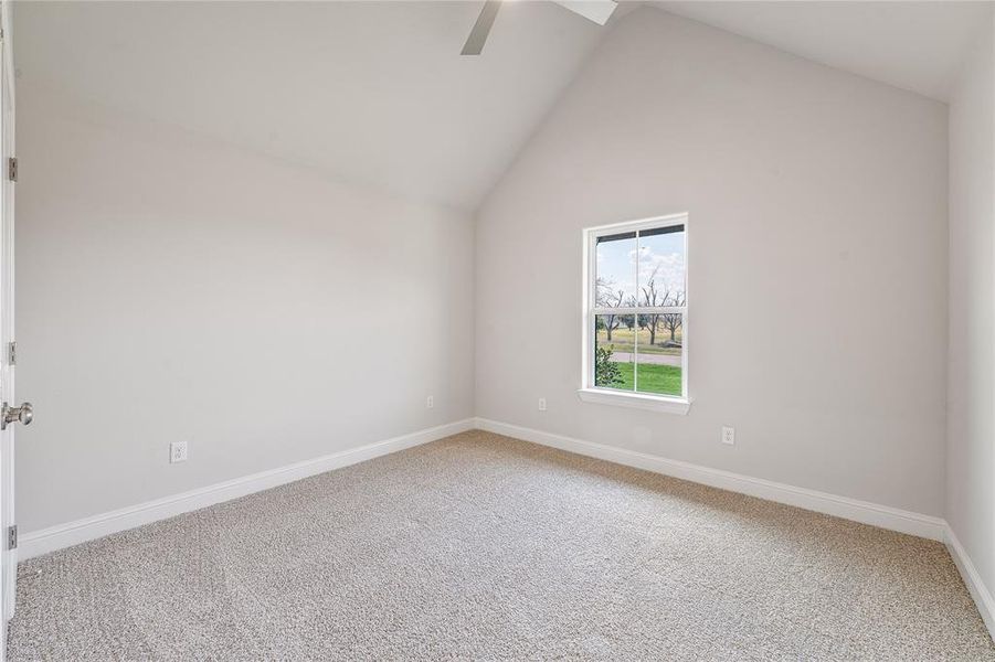Empty room with carpet flooring, high vaulted ceiling, and ceiling fan