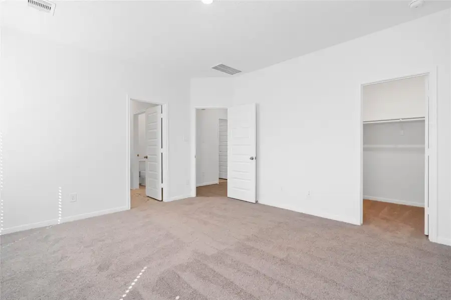 Additional perspective from primary bedroom looking towards walk-in closet and entrance to ensuite bathroom.