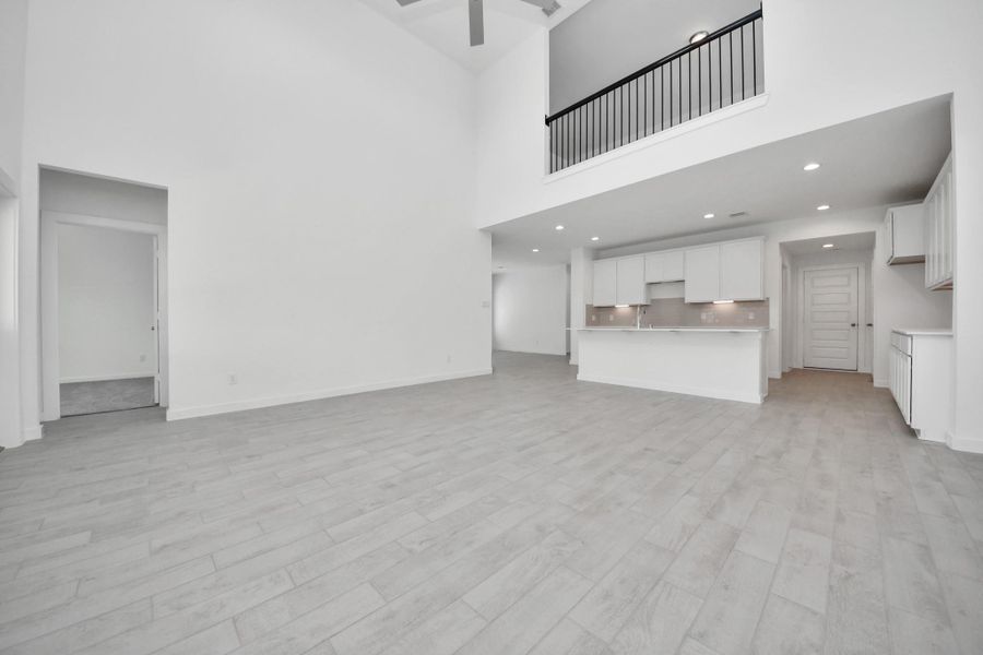 Gather the family and guests together in your lovely living room! Featuring soaring high ceilings, recessed lighting, ceiling fan, custom paint, gorgeous floors, and large windows that provide plenty of natural lighting throughout the day. Sample photo of completed home with similar floor plan. Actual colors and selections may vary.