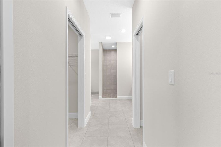 HALLWAY LEADING TO PRIMARY SUITE BATHROOM FROM BEDROOM AREA- POCKET DOOR OFFERS PRIVACY