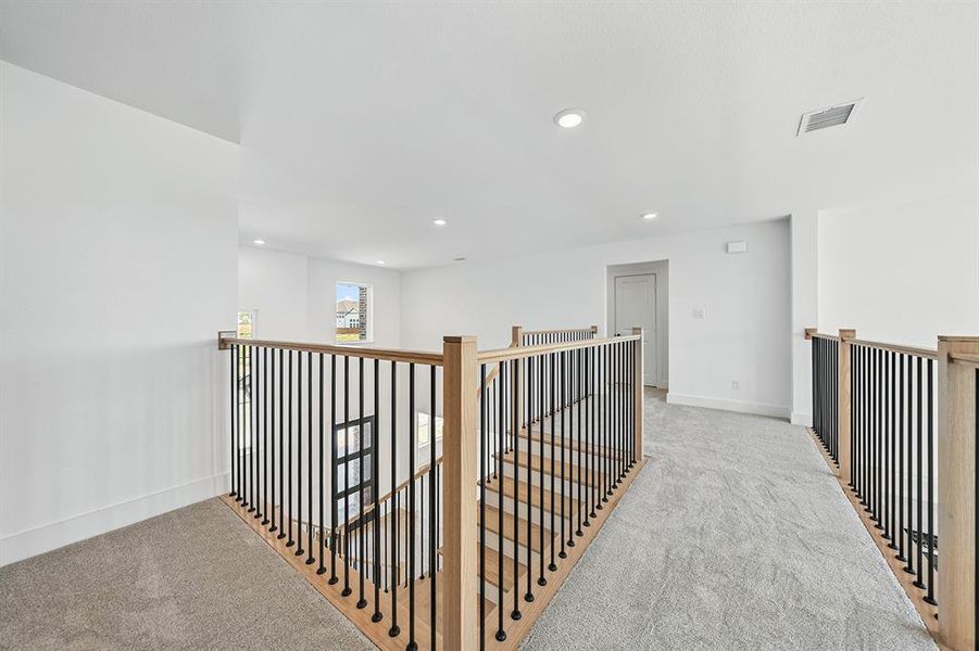 Hallway featuring light carpet, an upstairs landing, and recessed lighting