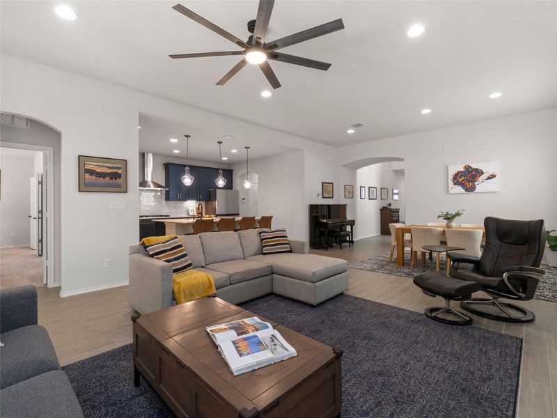 Living room with arched walkways, tile floors, ceiling fan, and recessed lighting