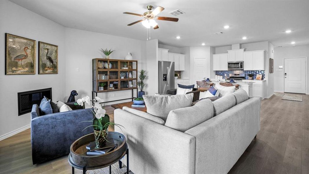 Living area with a glass covered fireplace, a ceiling fan, wood finished floors, and recessed lighting
