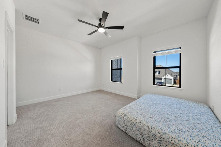 Bedroom with carpet floors, visible vents, baseboards, and a ceiling fan