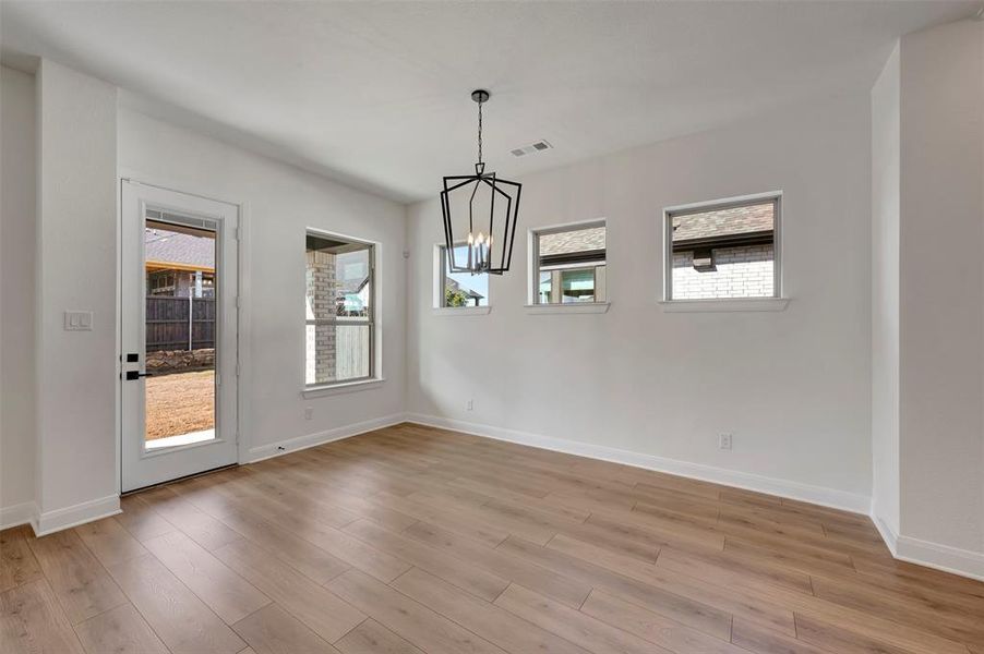 Unfurnished dining area with hanging lights and light wood-style floors