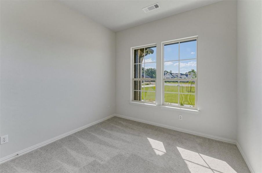 Neutral-toned room featuring a pair of double-hung windows with grid panes, light gray carpet, white baseboards, and a ceiling vent Neutral-toned room featuring a pair of double-hung windows with grid panes, light gray carpet, white baseboards, and a ceiling vent