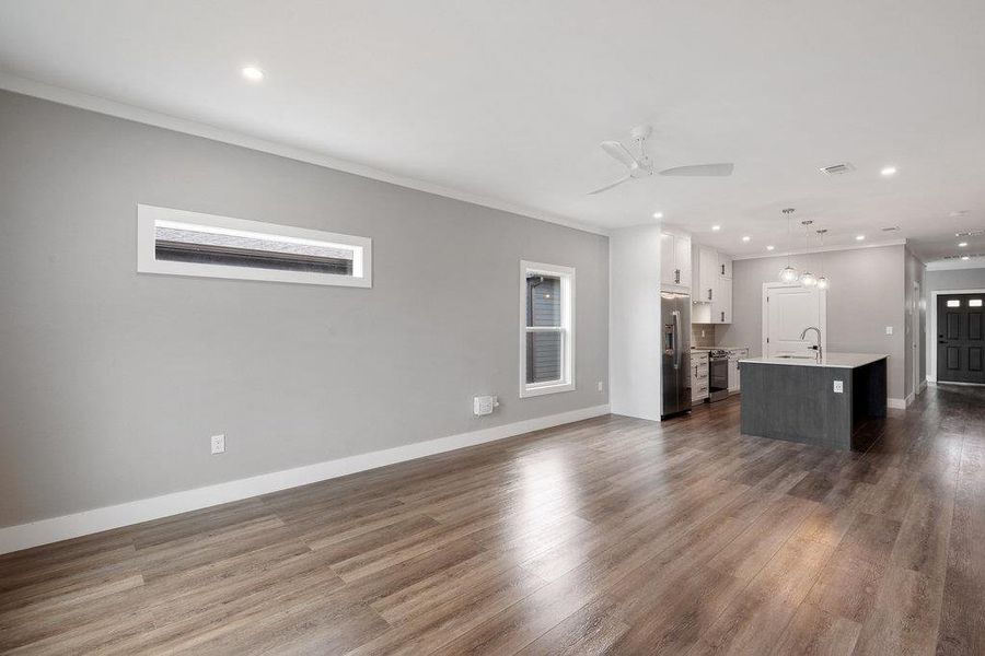 Unfurnished living room featuring crown molding, recessed lighting, dark wood-style floors, and a ceiling fan