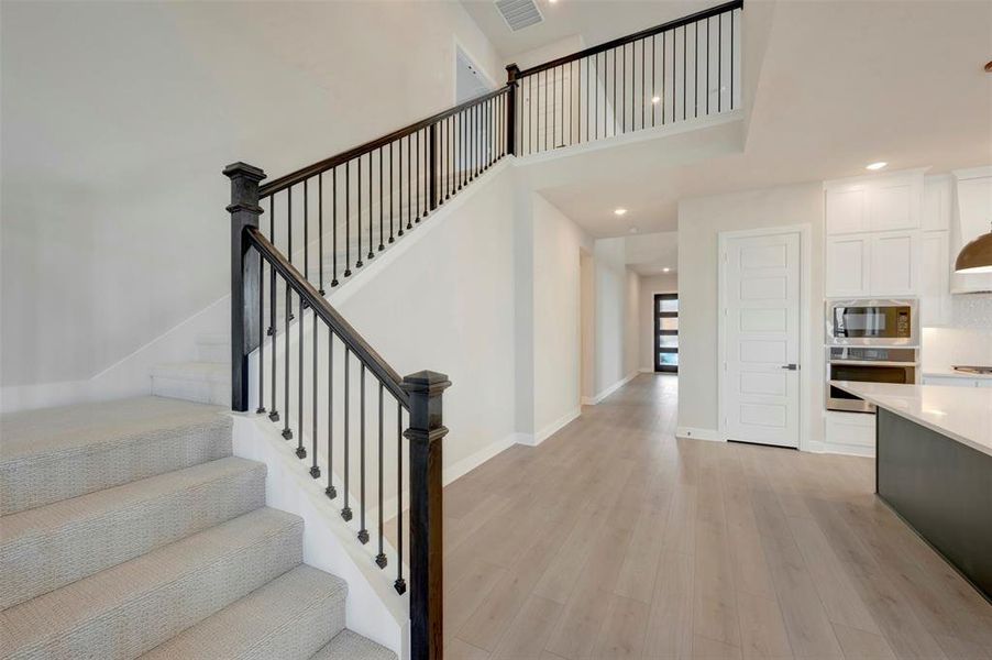 Stairs featuring wood finished floors, a high ceiling, and recessed lighting