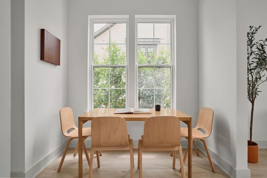 Dining space featuring two large sash windows, light wood-finish flooring, and white wall finishes