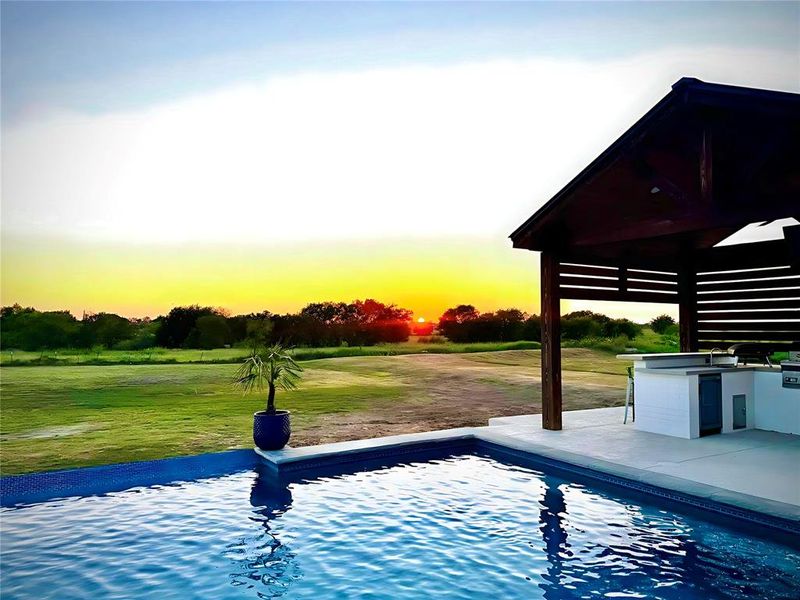Outdoor pool with exterior kitchen, a lawn, and a patio area