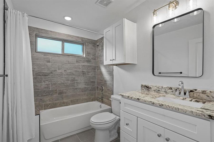 Full bathroom featuring vanity, toilet, tile patterned floors, and shower / bath combo