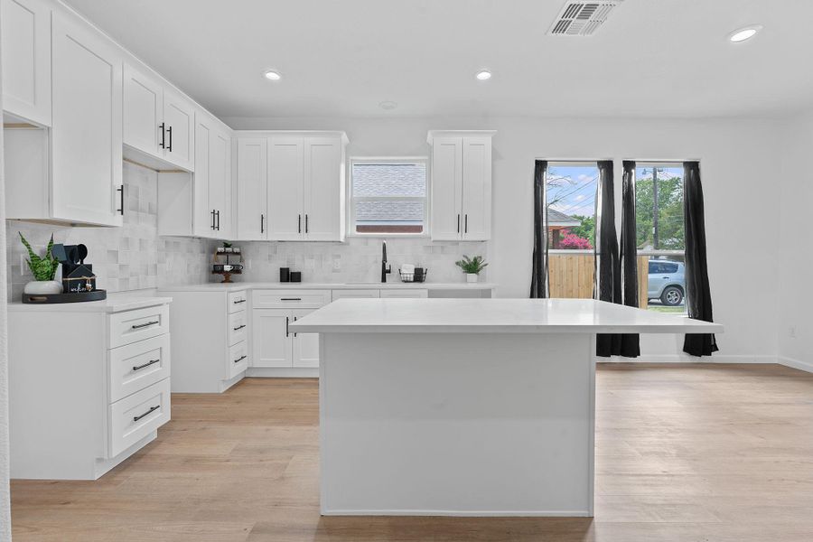 Kitchen featuring tasteful backsplash, recessed lighting, light wood-style flooring, light countertops, and white cabinets
