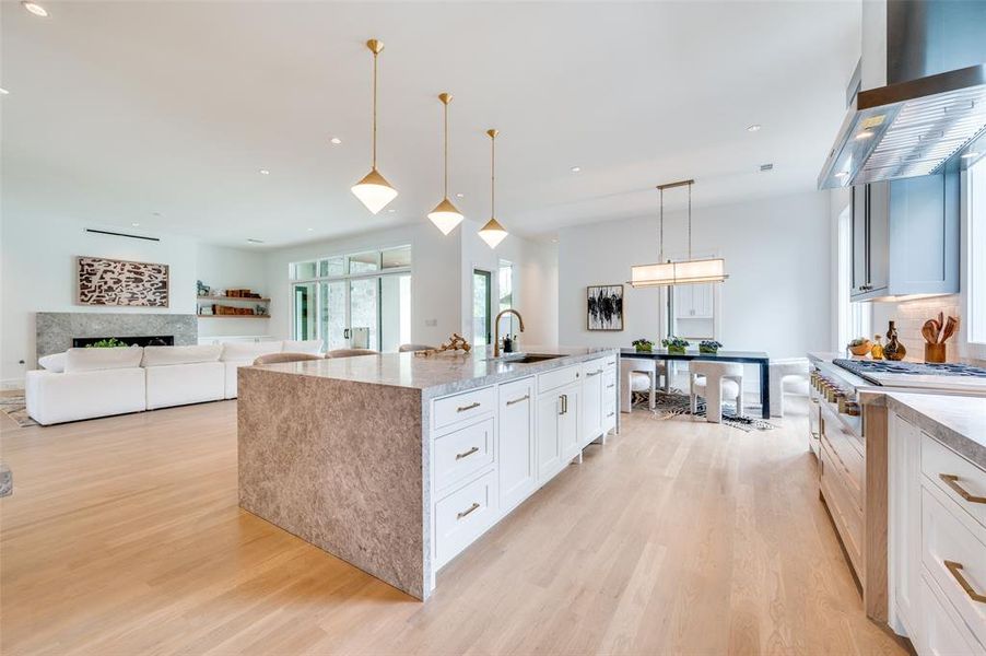 Kitchen featuring sink, white cabinetry, light wood-type flooring, and wall chimney range hood