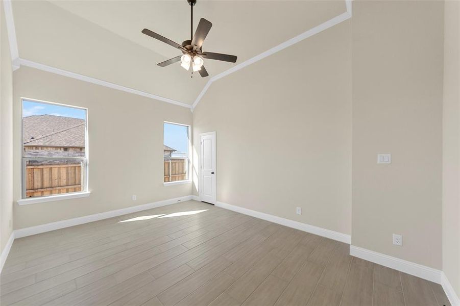 Unfurnished room featuring crown molding, light wood-style flooring, a ceiling fan, and vaulted ceiling Unfurnished room featuring crown molding, light wood-style flooring, a ceiling fan, and vaulted ceiling