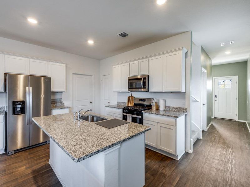 Kitchen featuring appliances with stainless steel finishes, light stone countertops, white cabinetry, dark wood-style flooring, and recessed lighting