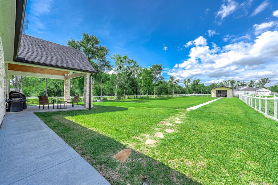 The backyard offers plenty of space to enjoy outdoor living, complete with a covered patio ideal for dining and entertaining. The expansive lawn extends to a large outbuilding that provides excellent potential for storage, a workshop, or additional utility space.