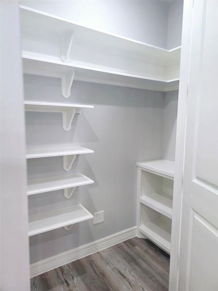 Walk-in pantry featuring multiple white shelves.
