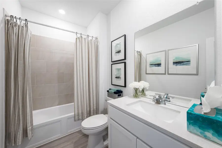 Full bath with shower / tub combo with curtain, vanity, and light wood-style floors