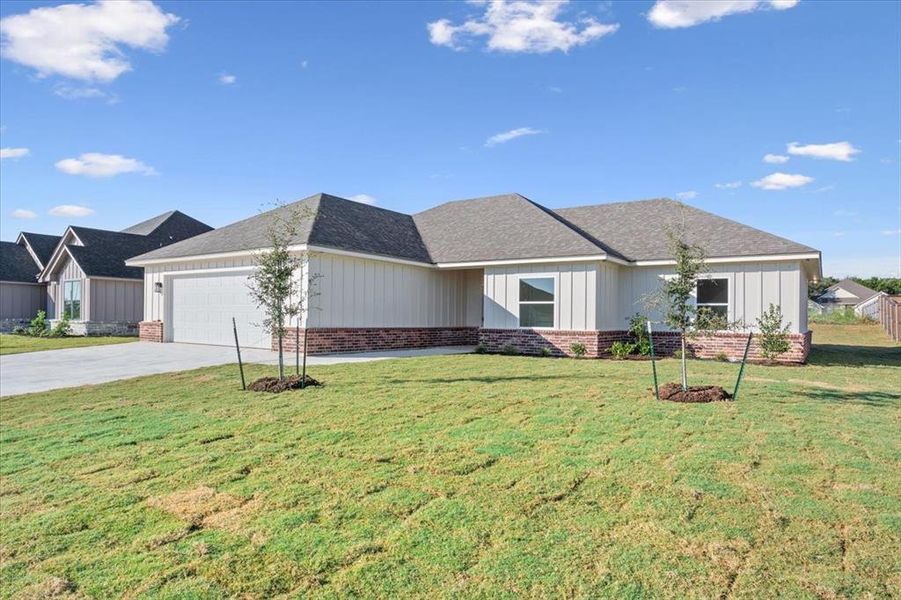 Single story home with driveway, a front lawn, a garage, and brick siding