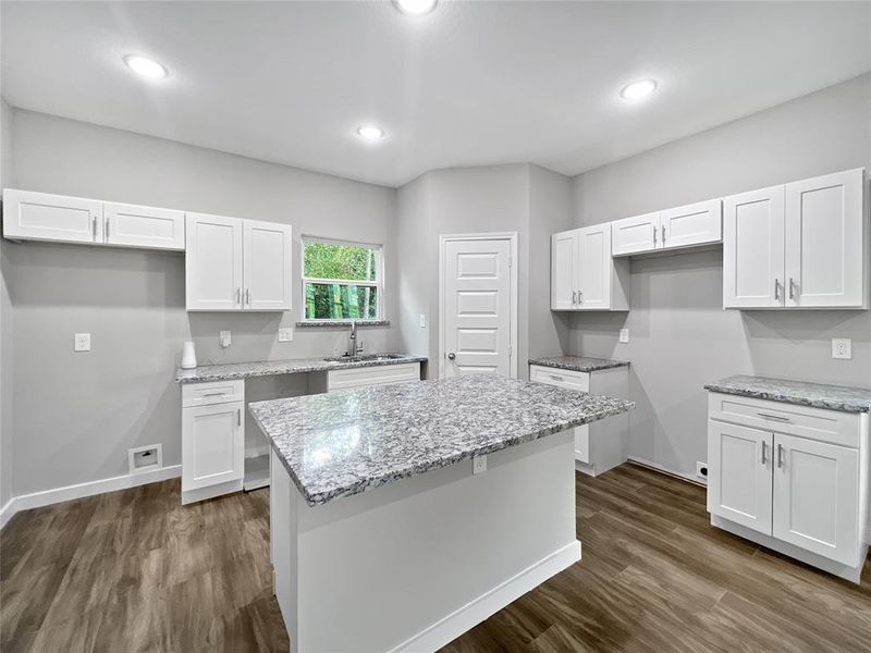 Kitchen featuring dark wood-type flooring, white cabinets, and a kitchen island