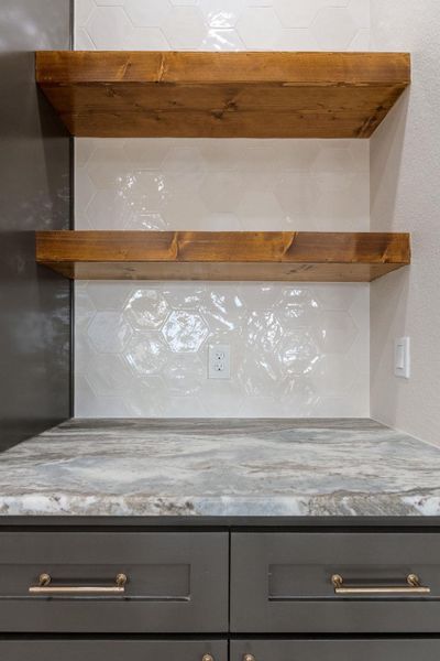 Detailed view of gray cabinets, light stone counters, and open shelves