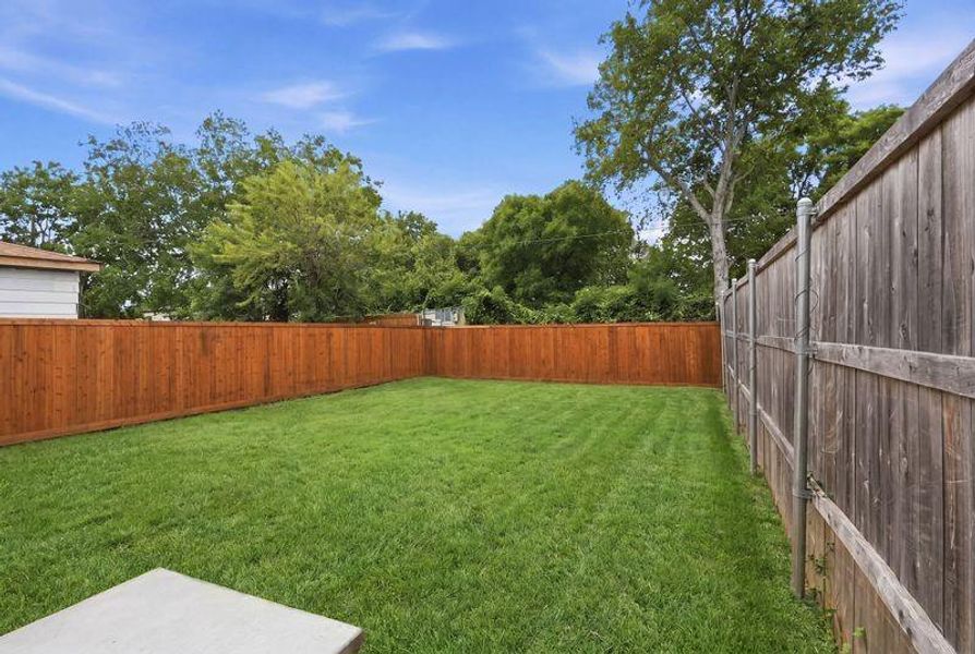 Expansive lawn area featuring a newly stained wooden fence on one side and a weathered wooden fence on the other Expansive lawn area featuring a newly stained wooden fence on one side and a weathered wooden fence on the other