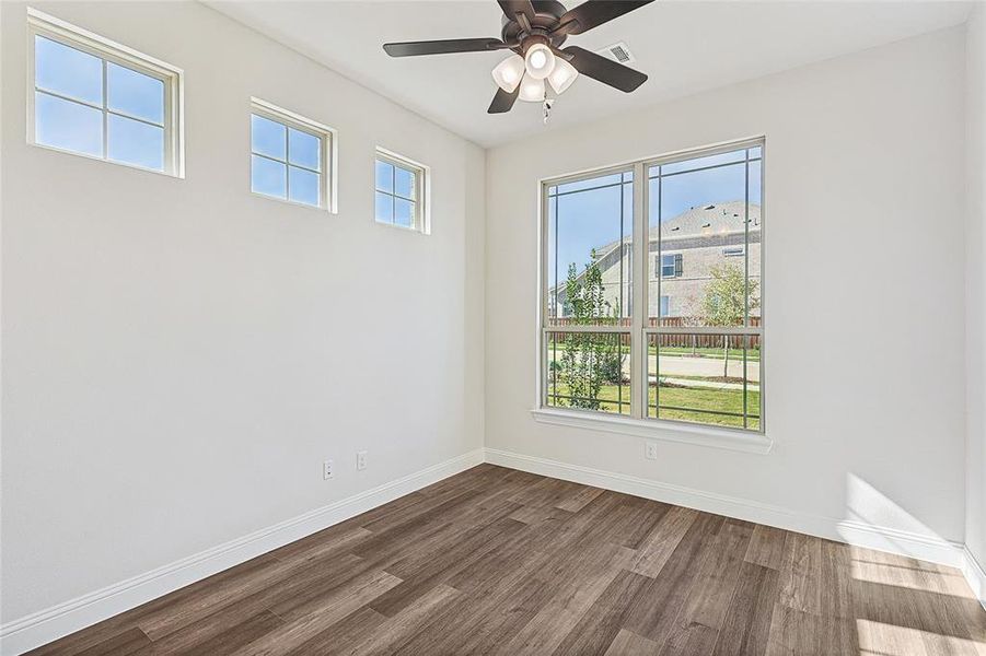 Empty room featuring ceiling fan, a healthy amount of sunlight, and dark hardwood / wood-style flooring