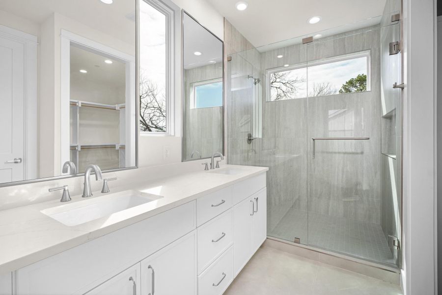 Primary bathroom featuring double vanity, a tiled extended shower, glass doors, and recessed lighting