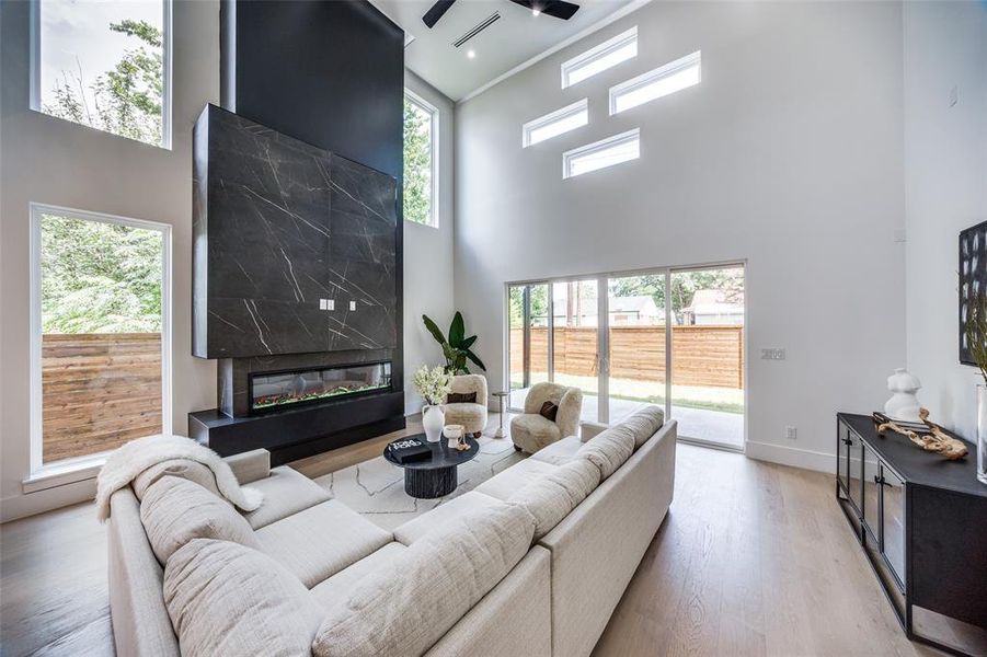 Living room with a high ceiling, a premium fireplace, and hardwood / wood-style floors