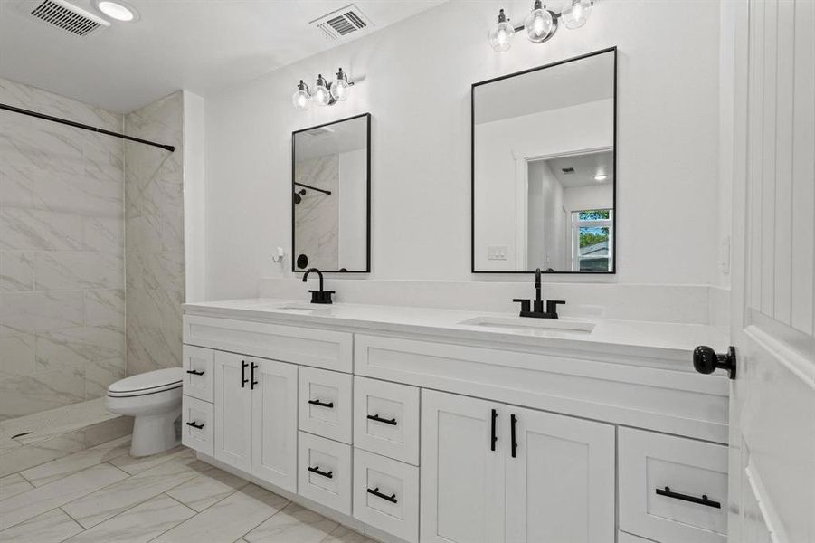 Bathroom featuring double vanity, a stall shower, light marble finish floors, and recessed lighting