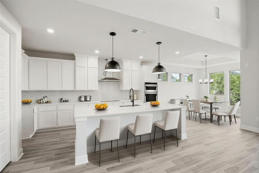 Kitchen with decorative backsplash, a kitchen breakfast bar, decorative light fixtures, light wood-style flooring, and recessed lighting