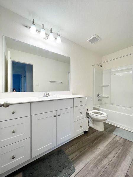 Full bathroom with  shower combination, vanity, and dark wood-type flooring