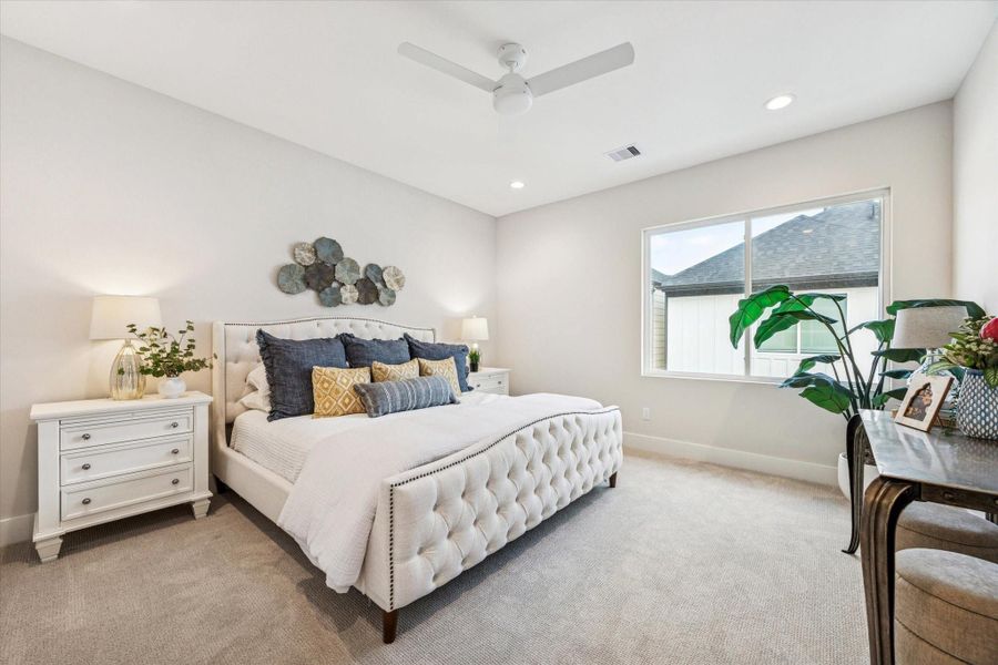 The spacious primary suite features recessed lighting, a ceiling fan, a large window, and a walk-in closet with built-ins.