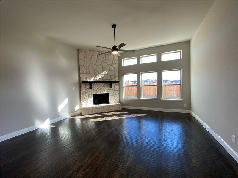 Family room offers a wall of windows, stone fireplace, Ebony hardwoods & a ceiling fan Family room offers a wall of windows, stone fireplace, Ebony hardwoods & a ceiling fan
