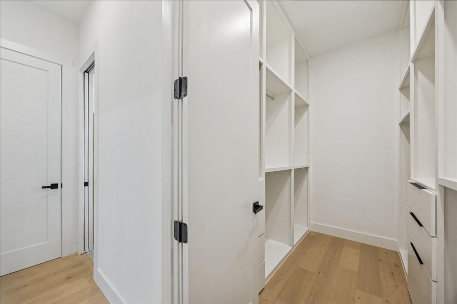 Custom primary walk-in closet featuring extensive built-in shelving, hanging space, and integrated drawer storage for effortless organization.