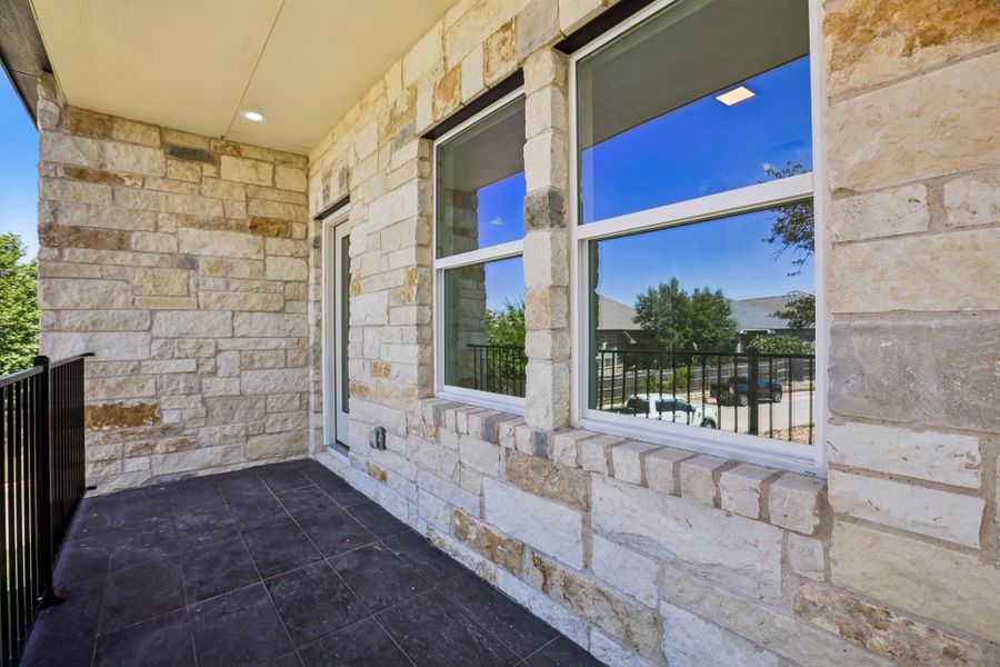 A covered stone patio offers a private outdoor retreat with sleek tile flooring.
