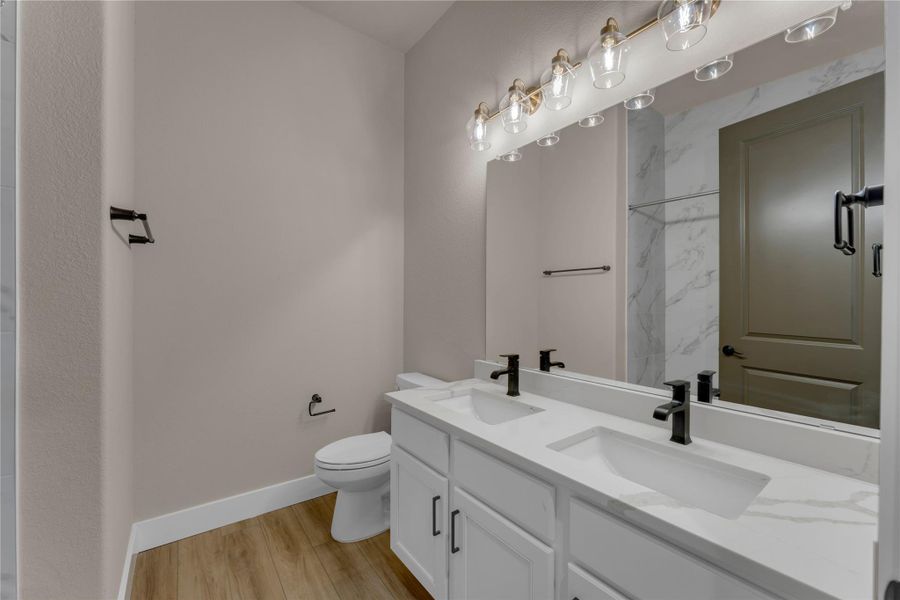 Bathroom with double vanity, light wood-style flooring, and a shower