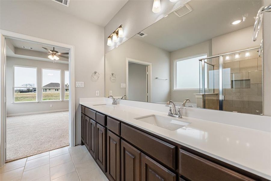 Bathroom featuring double vanity, a stall shower, light carpet, healthy amount of natural light, and recessed lighting