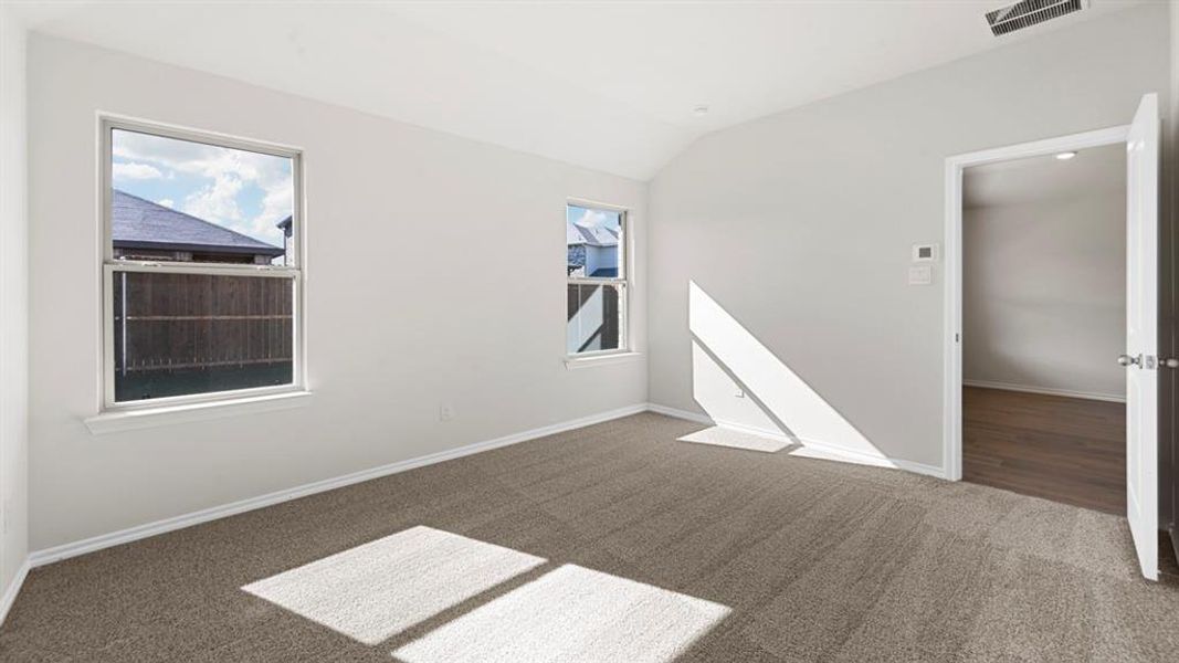 Empty room with vaulted ceiling and dark colored carpet