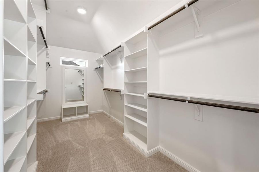 Walk in closet featuring light colored carpet and vaulted ceiling