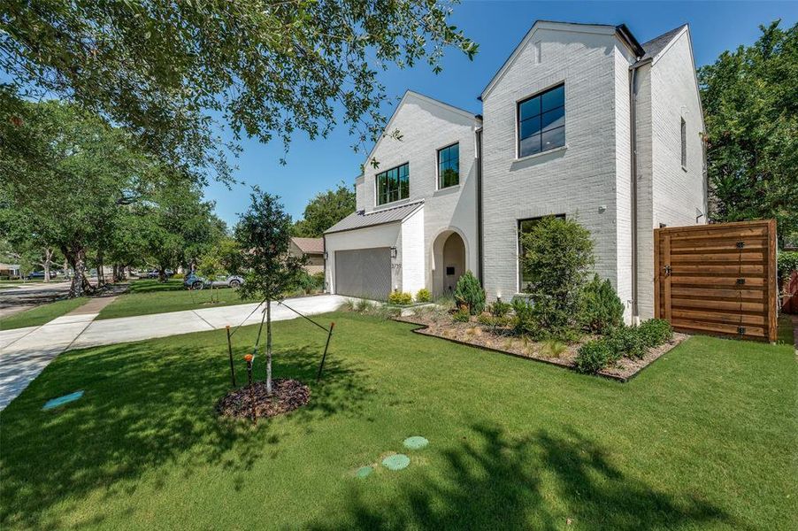 View of front of house with driveway, an attached garage, brick siding, and a front lawn